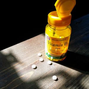 A jar of Vitamin D tablets highlighted by a beam of sunlight